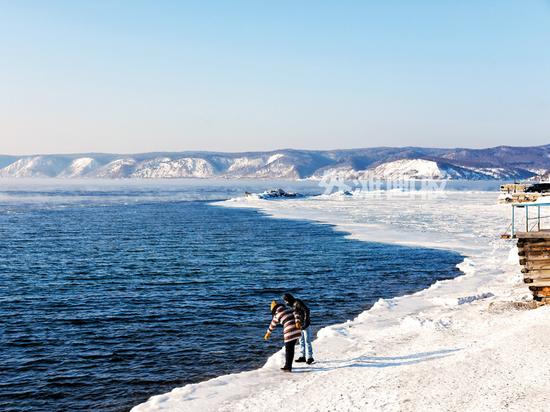 在贝加尔湖的最南端，最后一片流动的湖水等待着被冰封，两位旅客指向湖中的鱼儿
