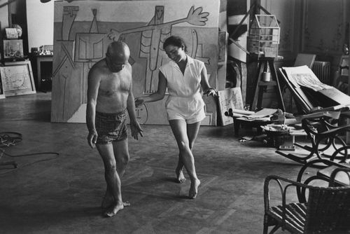 毕加索与妻子杰奎琳在在画作“Bañistas en La Garoupe ”前跳舞，1957年